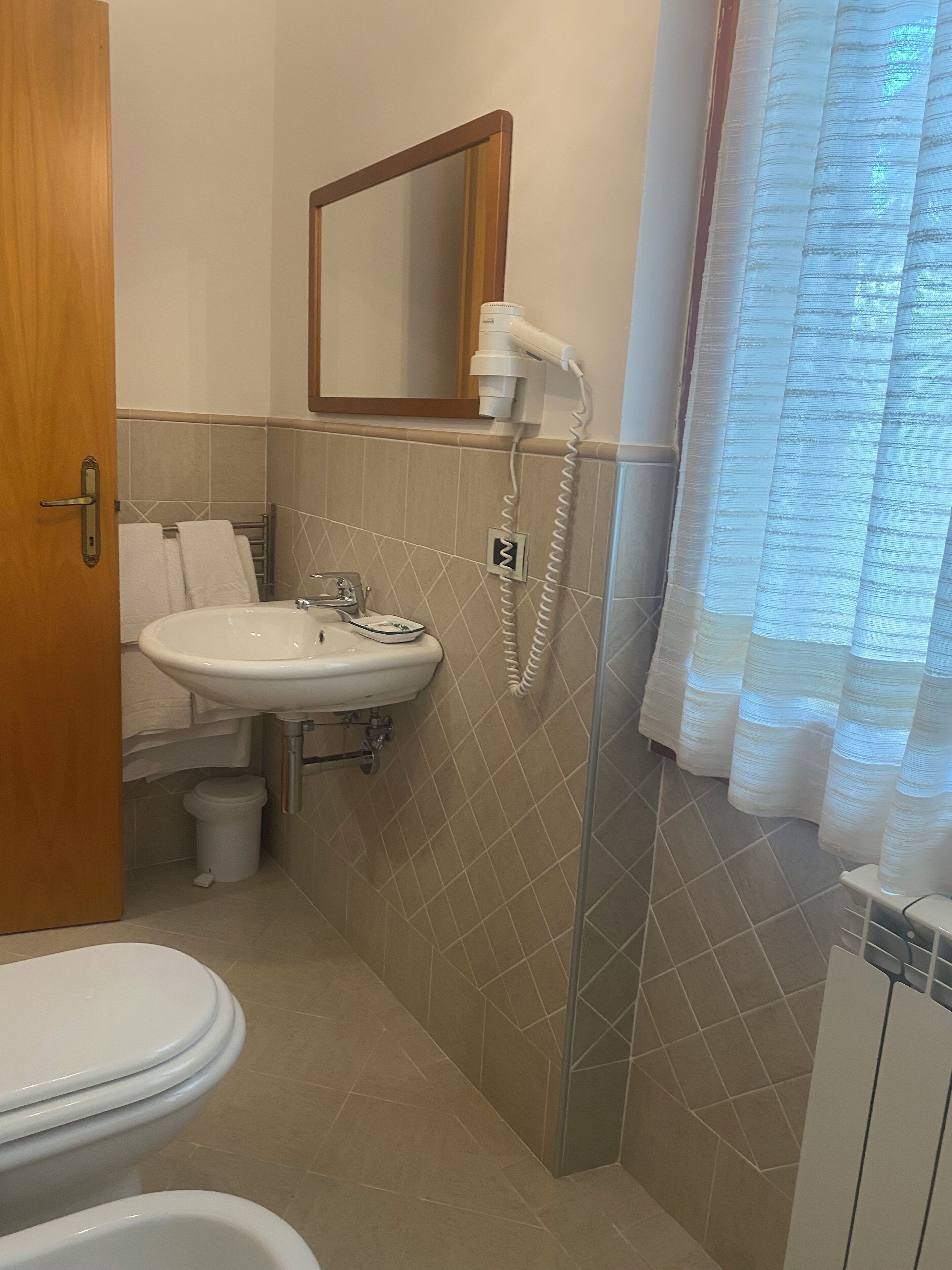 Une salle de bain équipée d’un lavabo, d’un miroir, d’un sèche-cheveux et de toilettes.