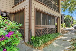 A two-story building with large windows, a visible staircase, and a well-maintained garden area. - Heron Pointe D1- 2 Bedroom Condo in Shore Drive (Myrtle Beach)