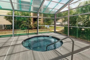 An indoor swimming pool with clear glass walls, surrounded by a metal fence and greenery. - Heron Pointe D1- 2 Bedroom Condo in Shore Drive (Myrtle Beach)