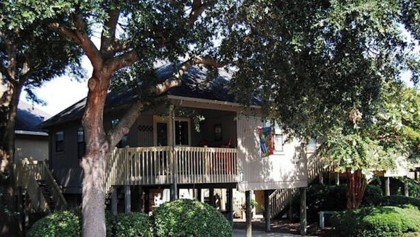 A two-story house with a balcony, surrounded by trees and bushes. - Guest Cottage 20- 2BR House- Community Pool (Myrtle Beach)
