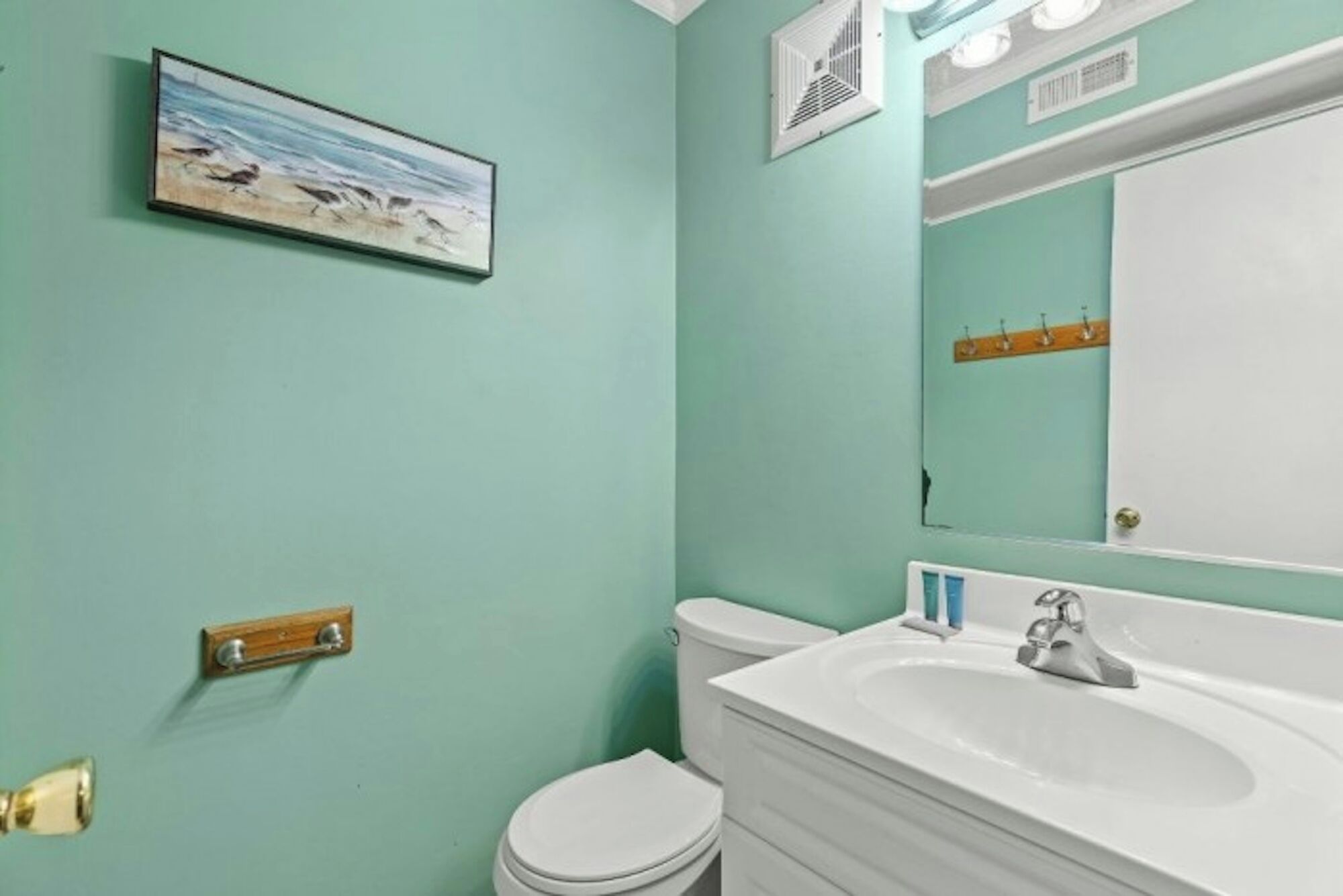 Un baño con un lavamanos blanco, un inodoro y un espejo.