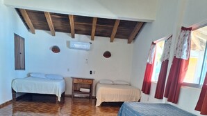 Una stanza con due letti, soffitto in legno, pavimento decorato e finestra con tende.