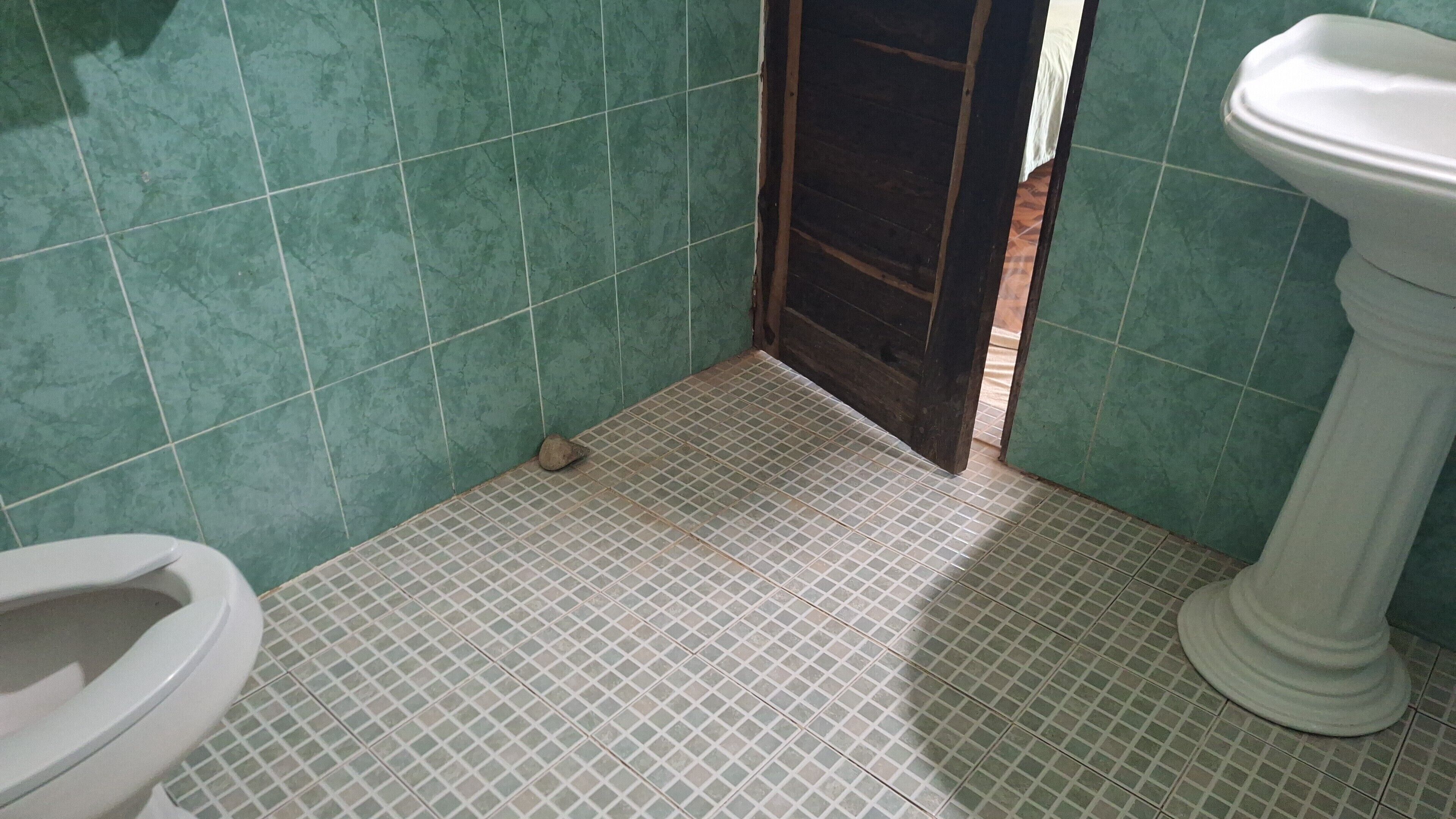 Un baño con inodoro, lavabo y una puerta que da a otra habitación.