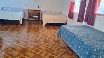 A room with three beds, wooden flooring, and a sloped ceiling.