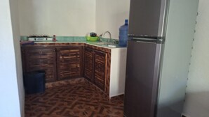 Una cucina compatta con mobili in legno, un frigorifero in acciaio inossidabile e uno schienale rivestito in piastrelle.