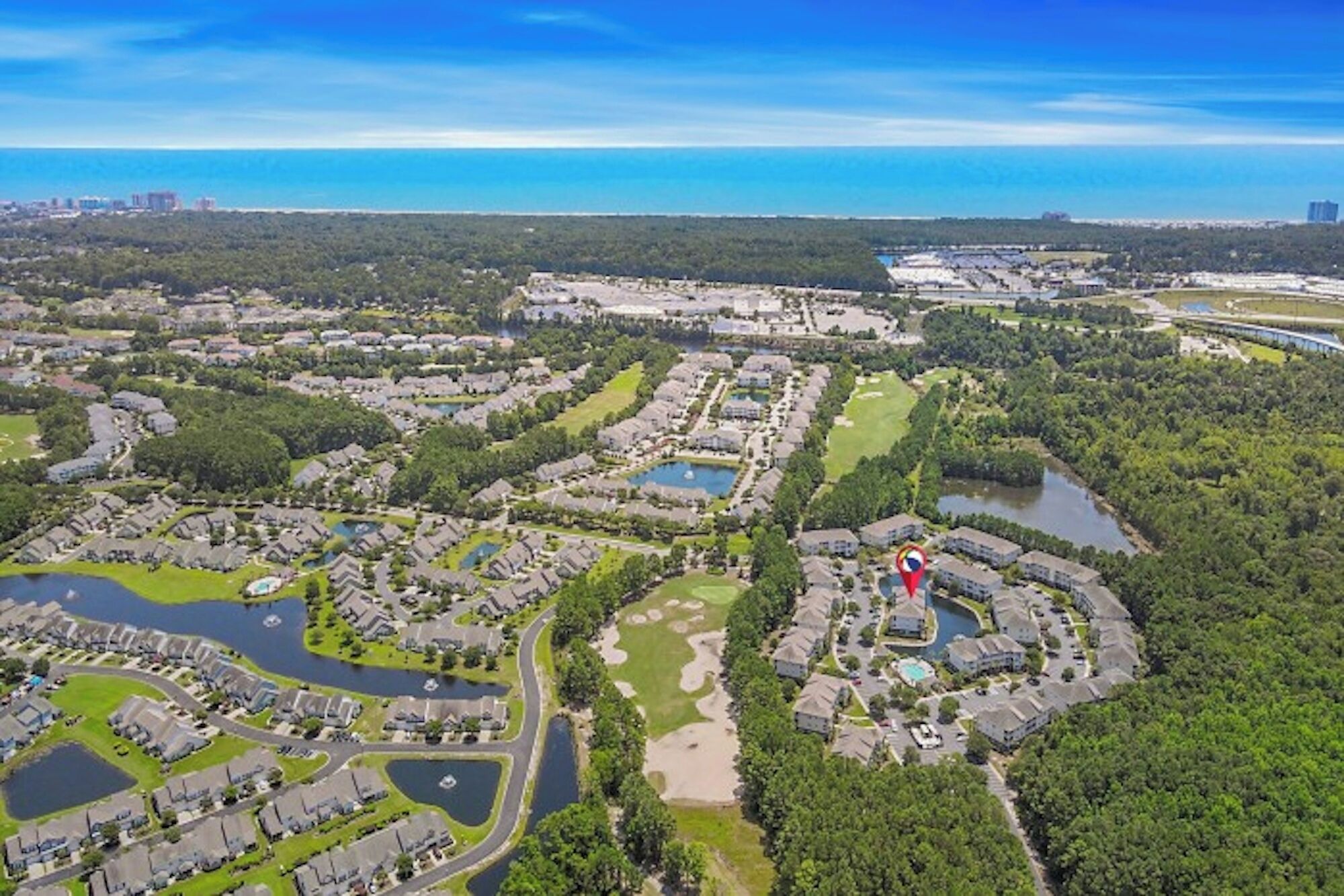 Vista aérea de una zona residencial con varios complejos de viviendas, áreas verdes y cuerpos de agua.