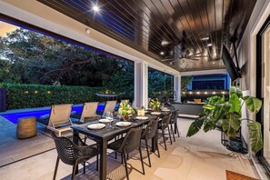 Un área de comedor al aire libre con piscina, sillas y una mesa dispuesta para una comida.