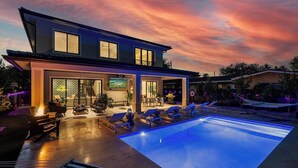 Una casa moderna con piscina, zona de estar exterior y barra.