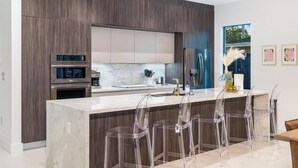 Una cocina moderna con encimera de mármol, electrodomésticos de acero inoxidable y un amplio ventanal.