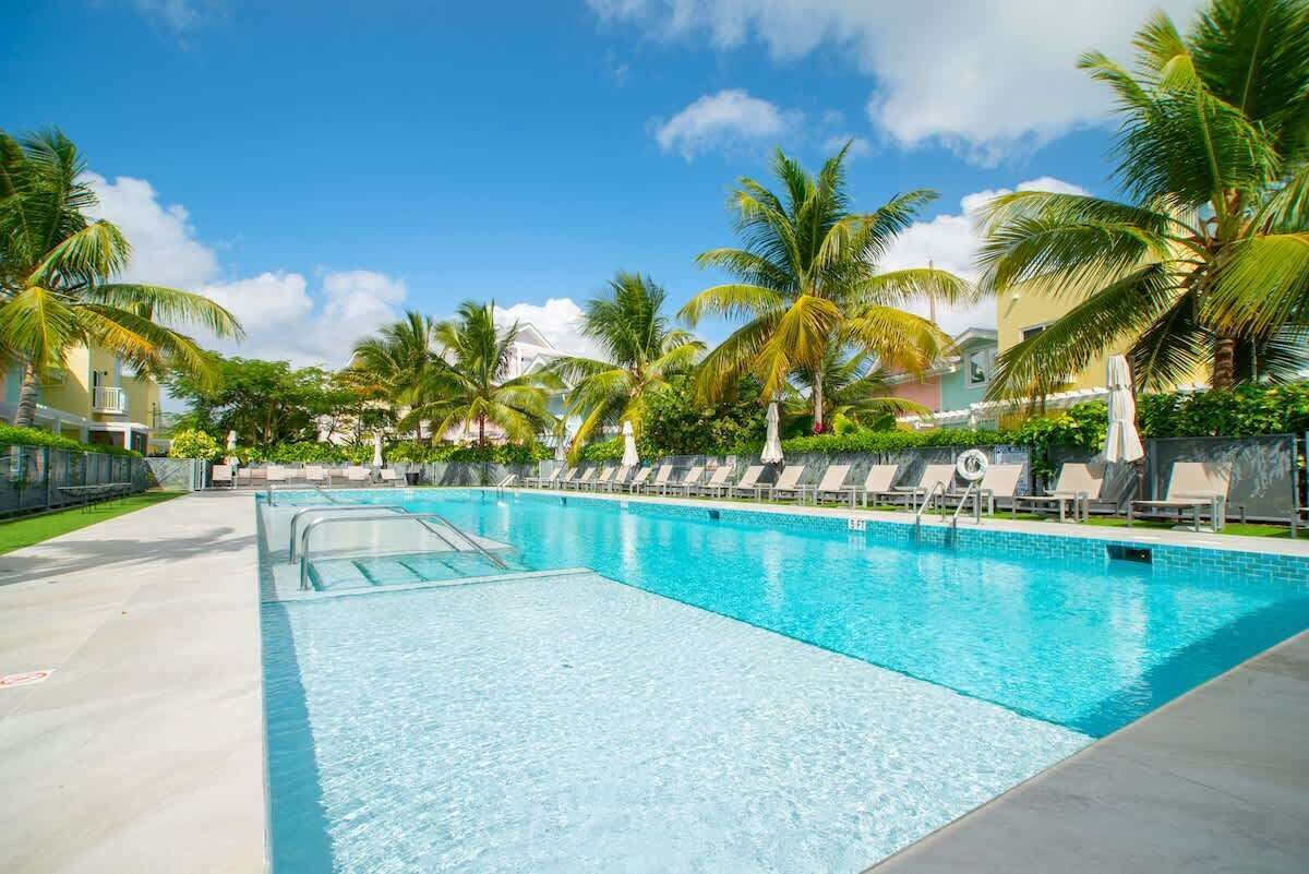 Una piscina con sillas de descanso y palmeras.