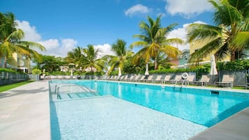 Una piscina con sillas de descanso y palmeras.