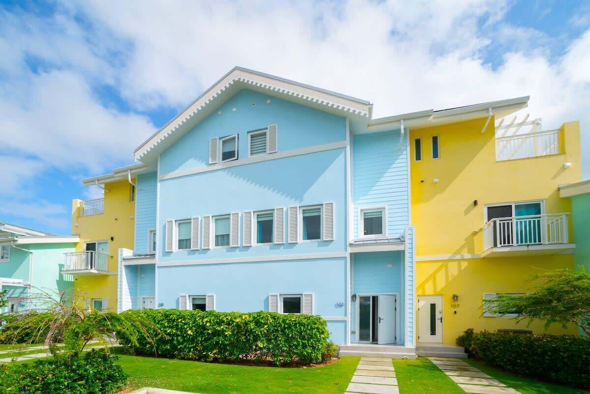 Un edificio residenziale a più piani con facciata azzurra, persiane bianche e balconi.