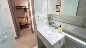 Un baño moderno con un lavabo blanco, un espejo y una pequeña planta en maceta.