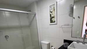 Un baño moderno con cabina de ducha de vidrio, inodoro, lavabo y espejo.
