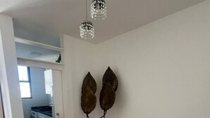 Ein Essbereich mit einem runden Tisch, transparenten Stühlen, einer Kristallleuchtre und Wanddekoration aus Blättern.