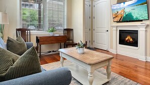 A living room with a fireplace, a television mounted on the wall, and a large window with blinds. - L-6 Gorgeous views, clean cozy near SDC (Branson)