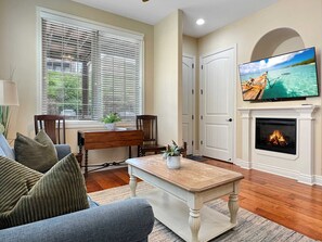A living room with a fireplace, a television mounted on the wall, and a large window with blinds. - L-6 Gorgeous views, clean cozy near SDC (Branson)