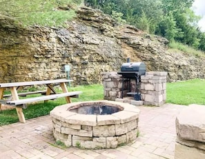 A stone fire pit and a barbecue grill in a landscaped area with a picnic table. - L-6 Gorgeous views, clean cozy near SDC (Branson)