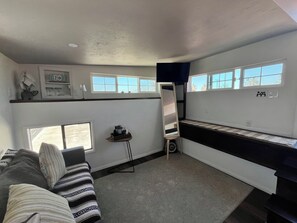 A compact living space with a sofa, a small table, and a kitchenette area.
