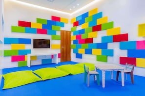 A room with a blue carpet, a wooden door, a white bench, a table with chairs, and colorful foam blocks on the walls. - Luxury in Los Cabos (San José del Cabo)