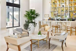 A modern lounge area with sofas, a coffee table, and a large potted plant. - Luxury in Los Cabos (San José del Cabo)
