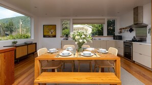 Une cuisine moderne avec une table à manger pour six personnes, entourée de chaises en osier.