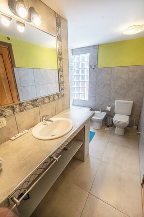 Un baño con lavamanos, bidé, inodoro y espejo.