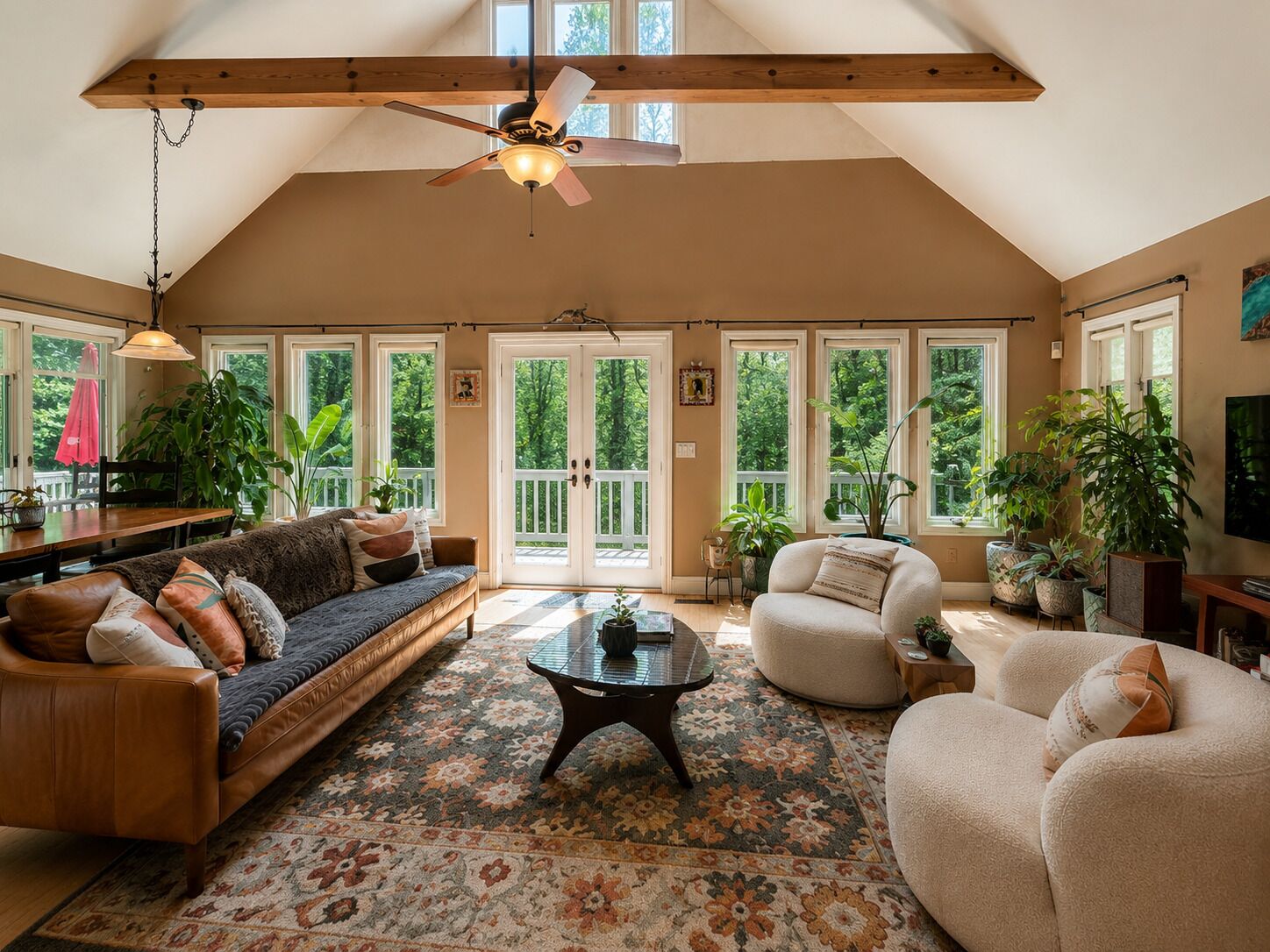 A spacious loft with a high ceiling, large windows, and a ceiling fan.
