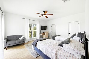 A bedroom with a bed, a sofa, a ceiling fan, a TV, and a window with curtains. - 3-4 bedroom west Austin house in charming Bee Cave with cool AC and epic views! (Bee Cave)