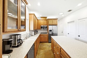 A modern kitchen with wooden cabinets, stainless steel appliances, and a granite countertop. - 3-4 bedroom west Austin house in charming Bee Cave with cool AC and epic views! (Bee Cave)