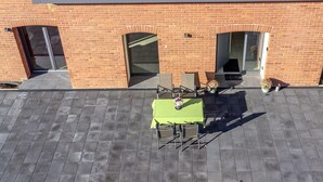 Kattoterassi, jossa on vihreä pöytä ja tuoleja, taustalla tiilinen rakennus ja tervetulotoivotus.