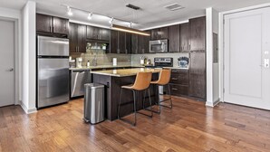 Une cuisine moderne avec des meubles en bois foncé, des appareils électroménagers en acier inoxydable et un îlot central doté de tabourets de bar.
