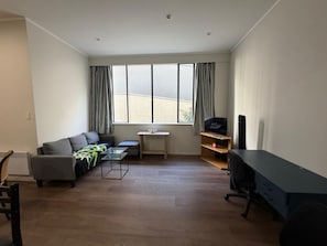 A modern living room with a sofa, a coffee table, a TV, and a desk.