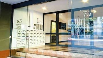 A hotel entrance with a glass facade, numbered room signs, and a visible staircase.