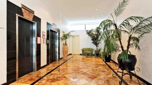 Un hall d’hôtel avec un sol en marbre, un comptoir d’accueil et des plantes en pot.