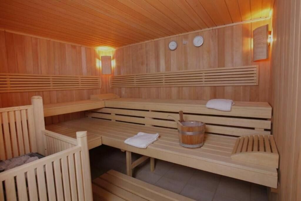 Een sauna met houten banken, een emmer en handdoeken.