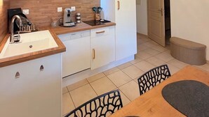 A compact kitchen with white cabinets, a wooden countertop, a built-in stove, and a modern light fixture.