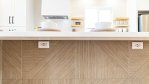 Une cuisine avec un plan de travail en bois, des armoires blanches et un crédence décorée.