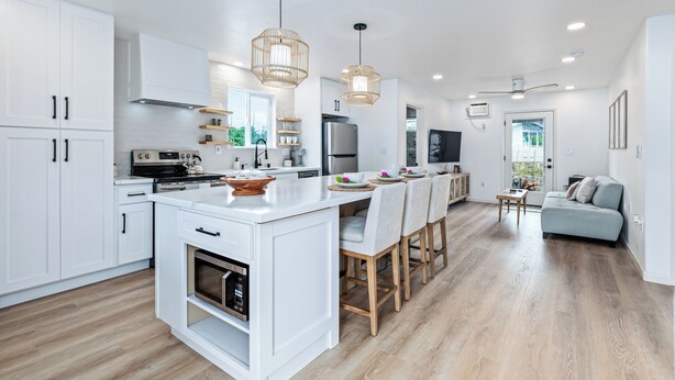 Une cuisine moderne avec des meubles blancs, un îlot central et des luminaires suspendus.
