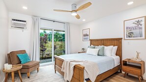 Une chambre à coucher avec un lit, une chaise, une table de chevet et un ventilateur de plafond.