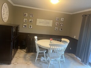 A dining area with a round table, white chairs, and a 'WELCOME' sign on the wall. - World Cup - Hot Tub, Bar, Gym- 15 Min to Arrowhead (Kansas City)