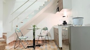 Una cocina compacta con refrigerador, lavamanos y comedor con dos sillas y una mesa.