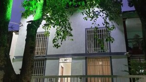 Un edificio de dos pisos con ventanas protegidas por barrotes y una entrada con puerta de acceso.