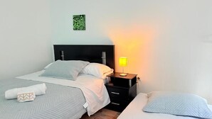 Un dormitorio con dos camas, una mesita de noche con lámpara y una obra de arte en la pared.