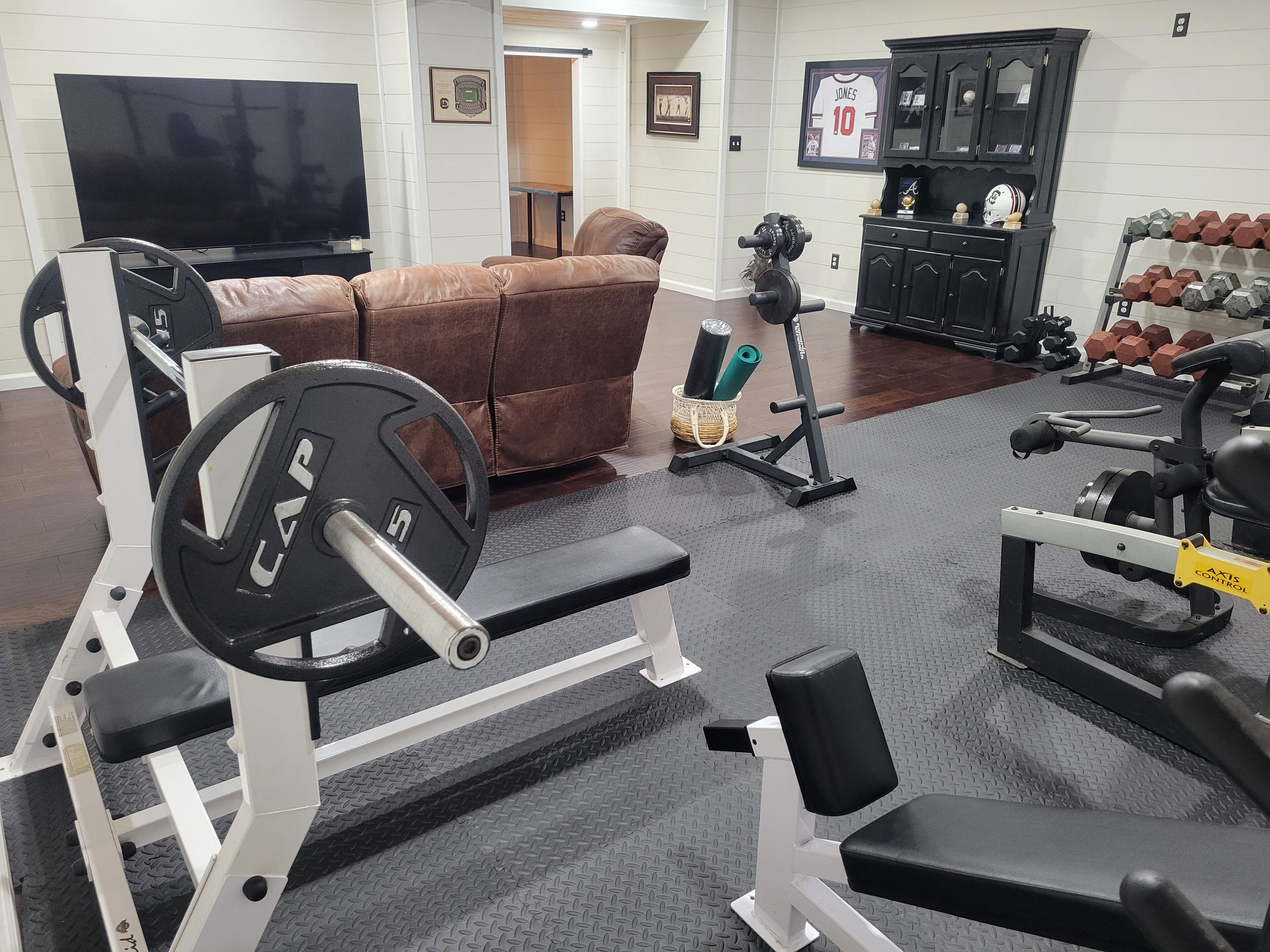 A home gym with a weight bench, squat rack, and various weights.