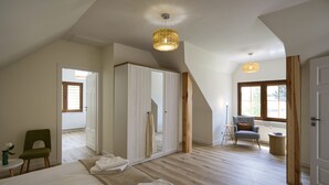 A bedroom with a large bed, a wardrobe, a chair, and a small table.