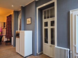 Ein Flur mit einem weißen Kühlschrank, einer Tür mit Glasverkleidung und einem Heizkörper an der Wand.