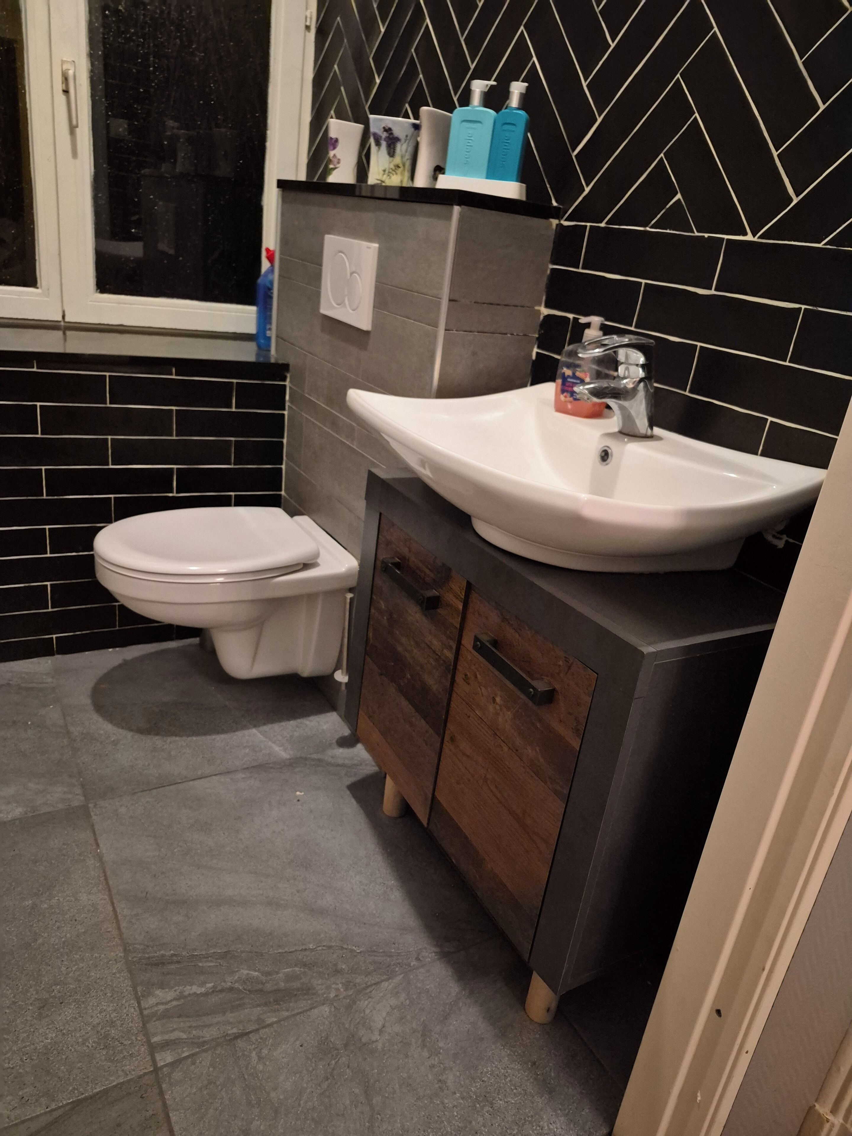 A bathroom with a toilet, a sink, and a cabinet.