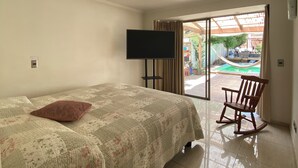 A bedroom with a bed, a TV, a rocking chair, and a sliding glass door leading to an outdoor area. - Comfortable and spacious house in Chicureo (Chicureo)