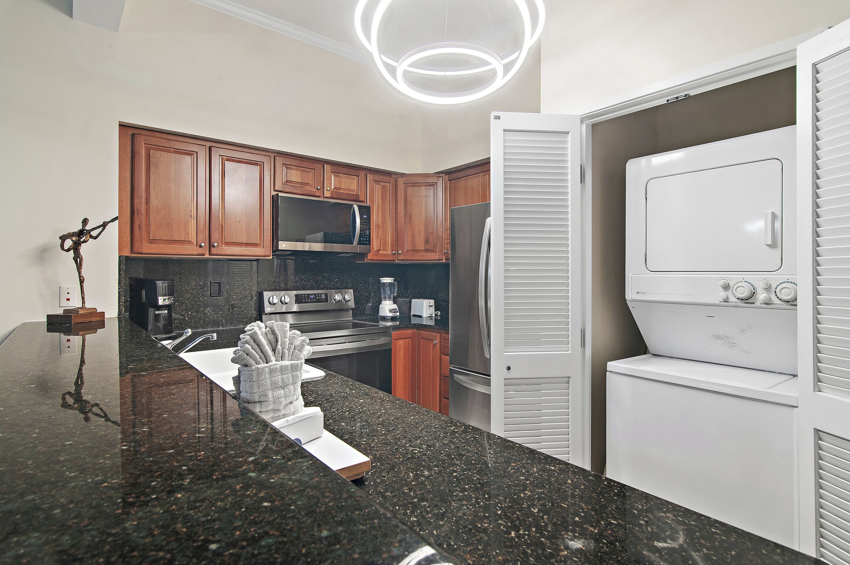A modern kitchen with wooden cabinets, stainless steel appliances, and a built-in washer and dryer.